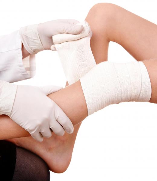 A medical professional wrapping a person's knee with a sports bandage.
