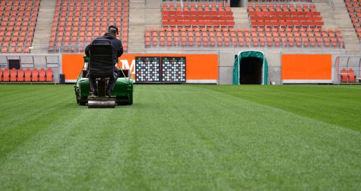 Football is played on meticulously groomed fields or indoor artificial turf.