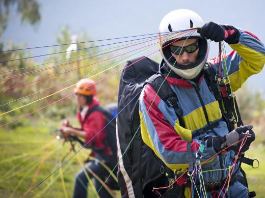 A paraglider checks the lines connecting his harness.
